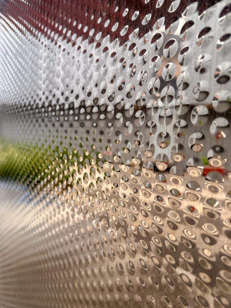 Close-up of a metallic, perforated surface with a textured pattern.