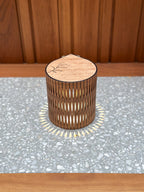 Wooden cylindrical lamp with engraved botanical on a gray surface