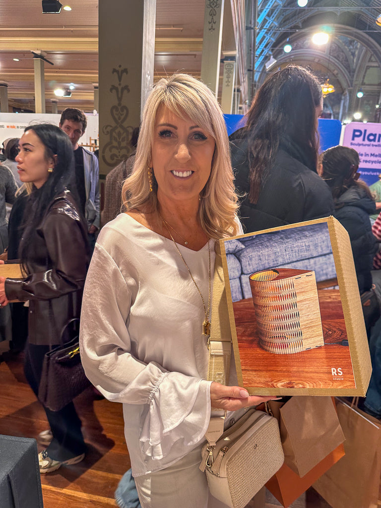 Woman holding a droplet lamp box in a busy indoor setting