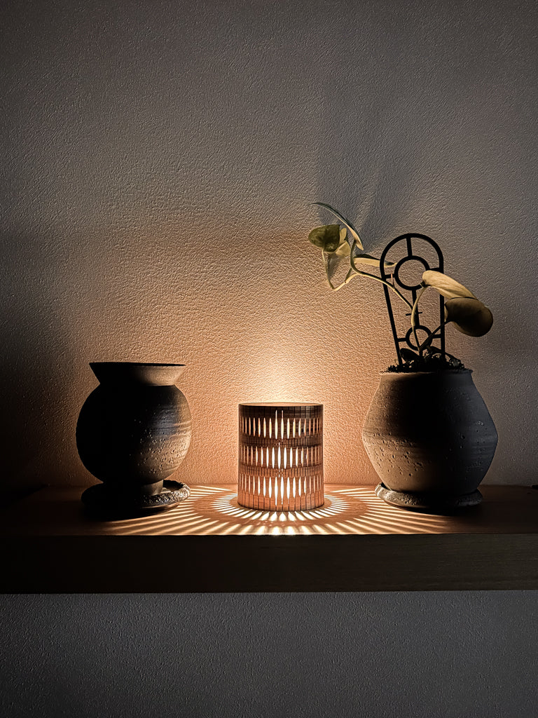 Three decorative objects casting shadows on a wall with warm lighting.