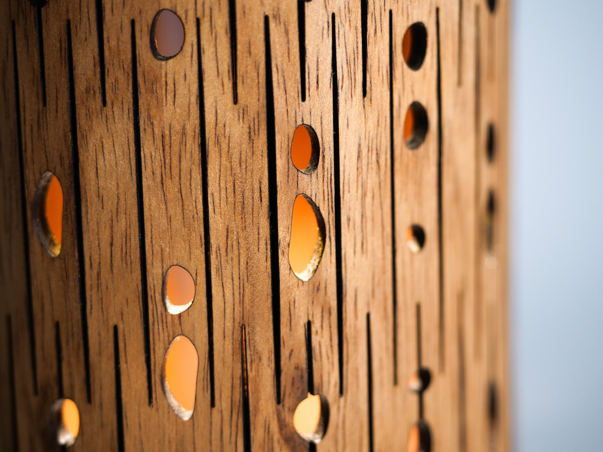 Close-up of perforated wooden candle holder with warm light glowing through holes