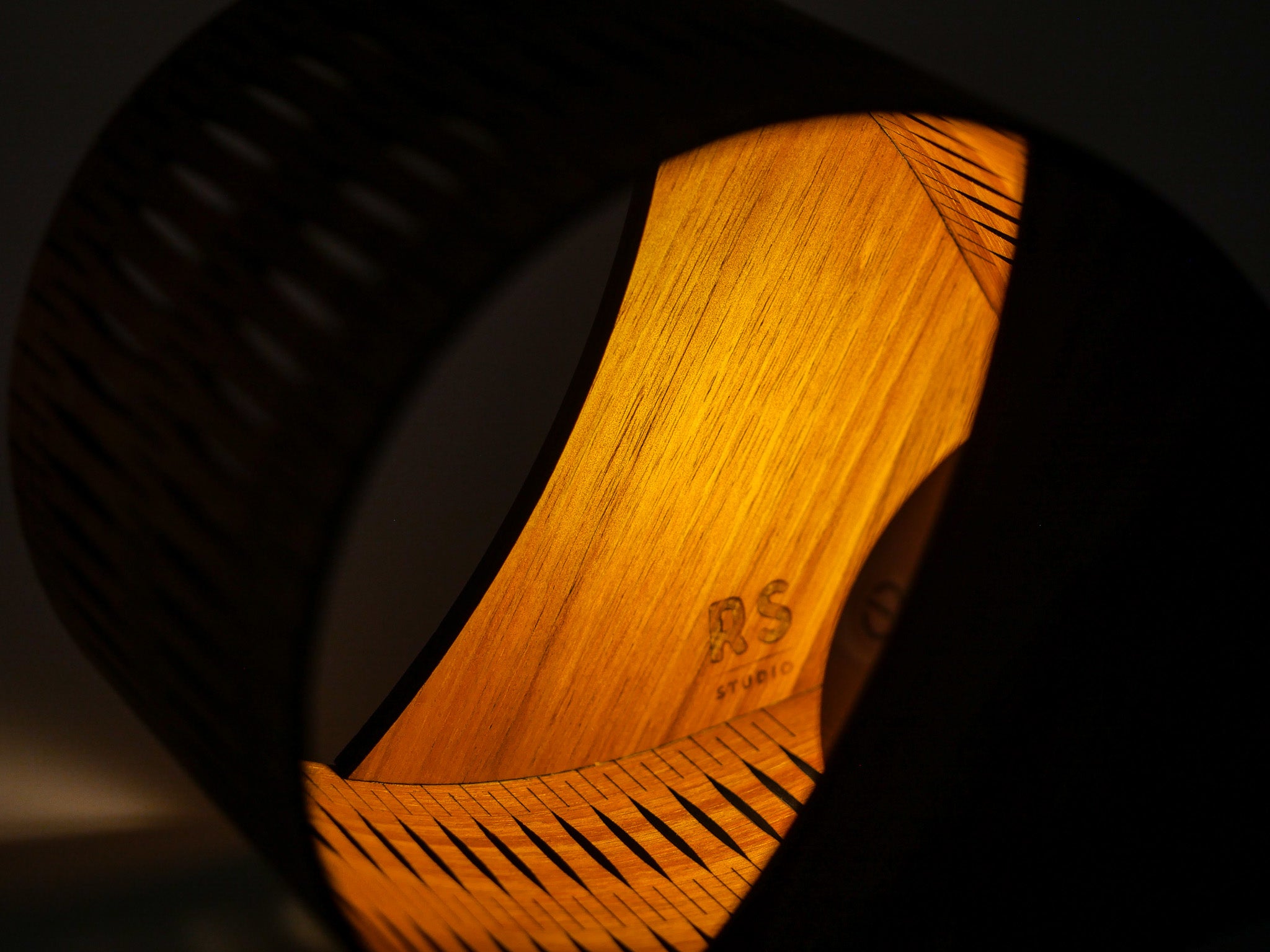 Close-up of a wooden droplet lamp with 'RS' branding on a dark background
