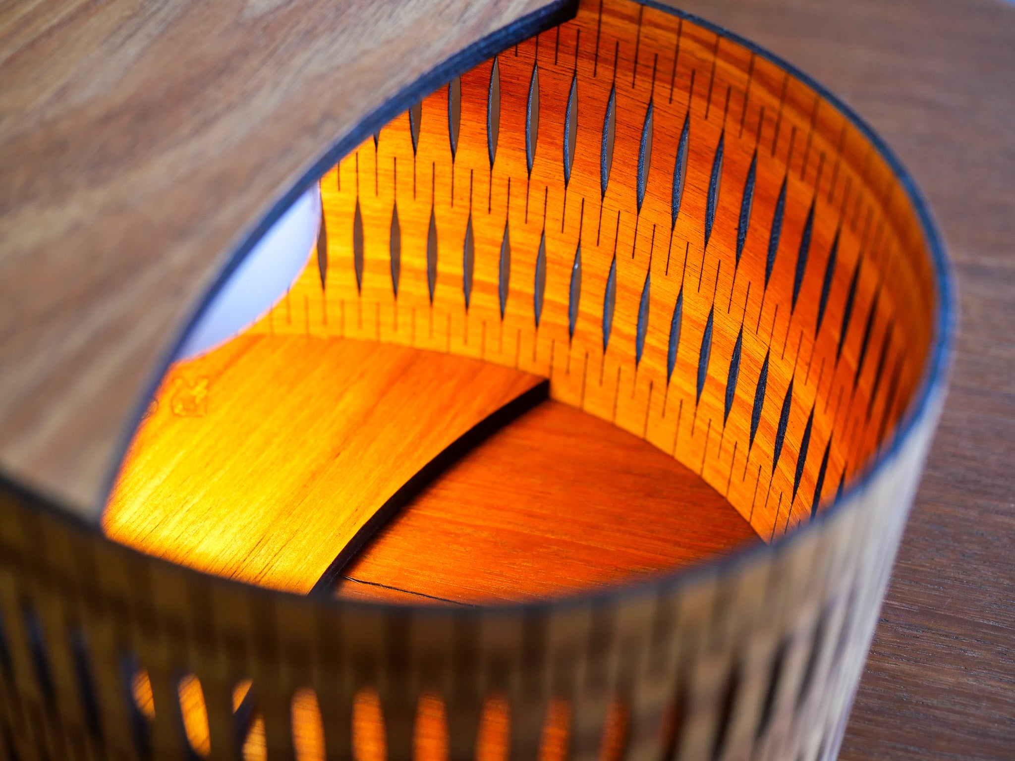 Timber droplet lamp glowing inside on a wooden surface