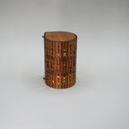 Wooden cylindrical lamp with decorative patterns on a gray background