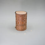 Cylindrical wooden lamp with decorative patterns on a gray background