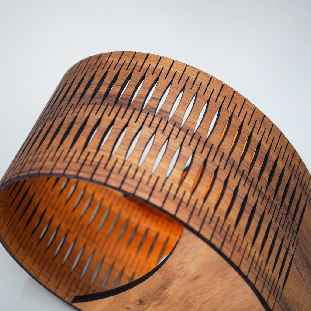 Wooden lampshade with a unique cut-out design on a white background
