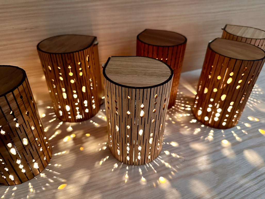 Set of wooden lamps with perforated design on a light wooden shelf.