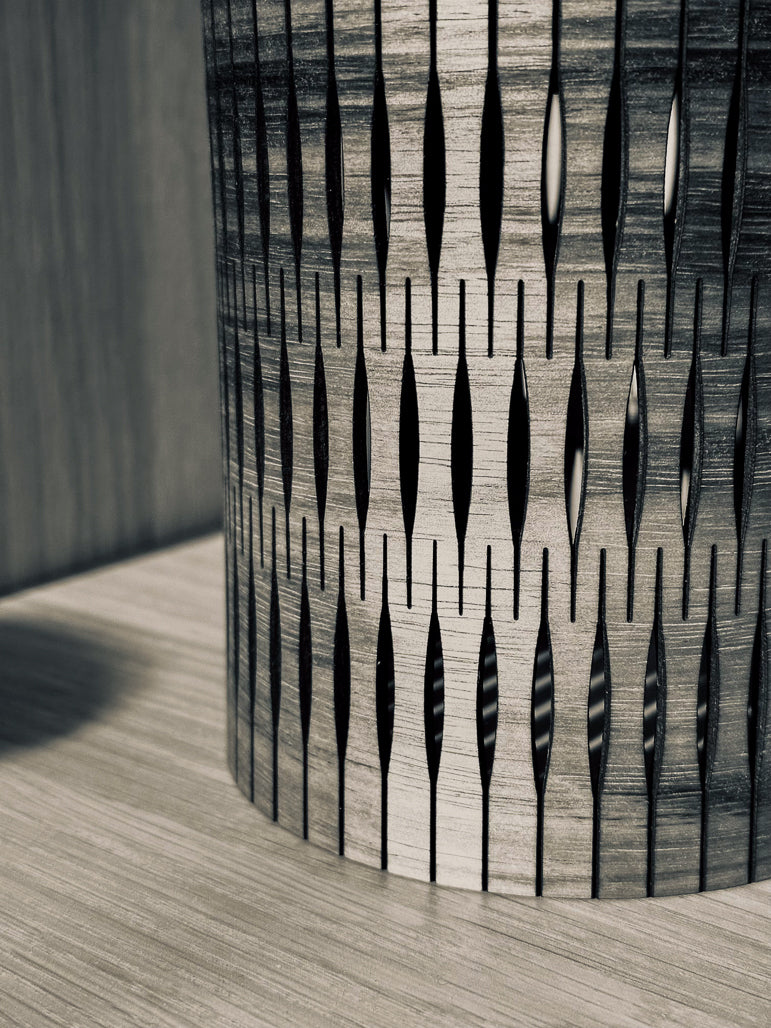 Decorative cylindrical object with a geometric pattern on a wooden surface